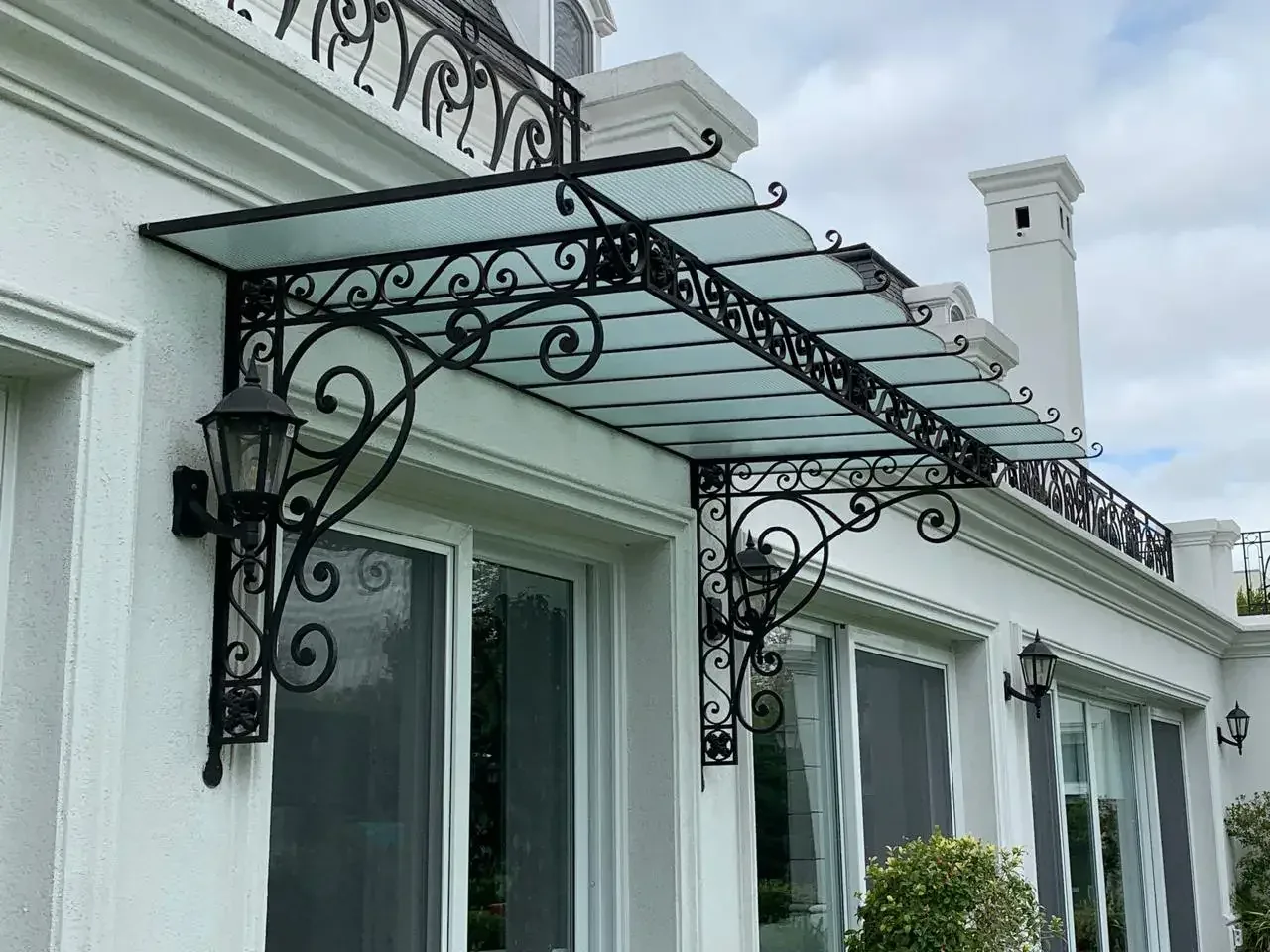 Alero ornamental de hierro y vidrio sobre abertura