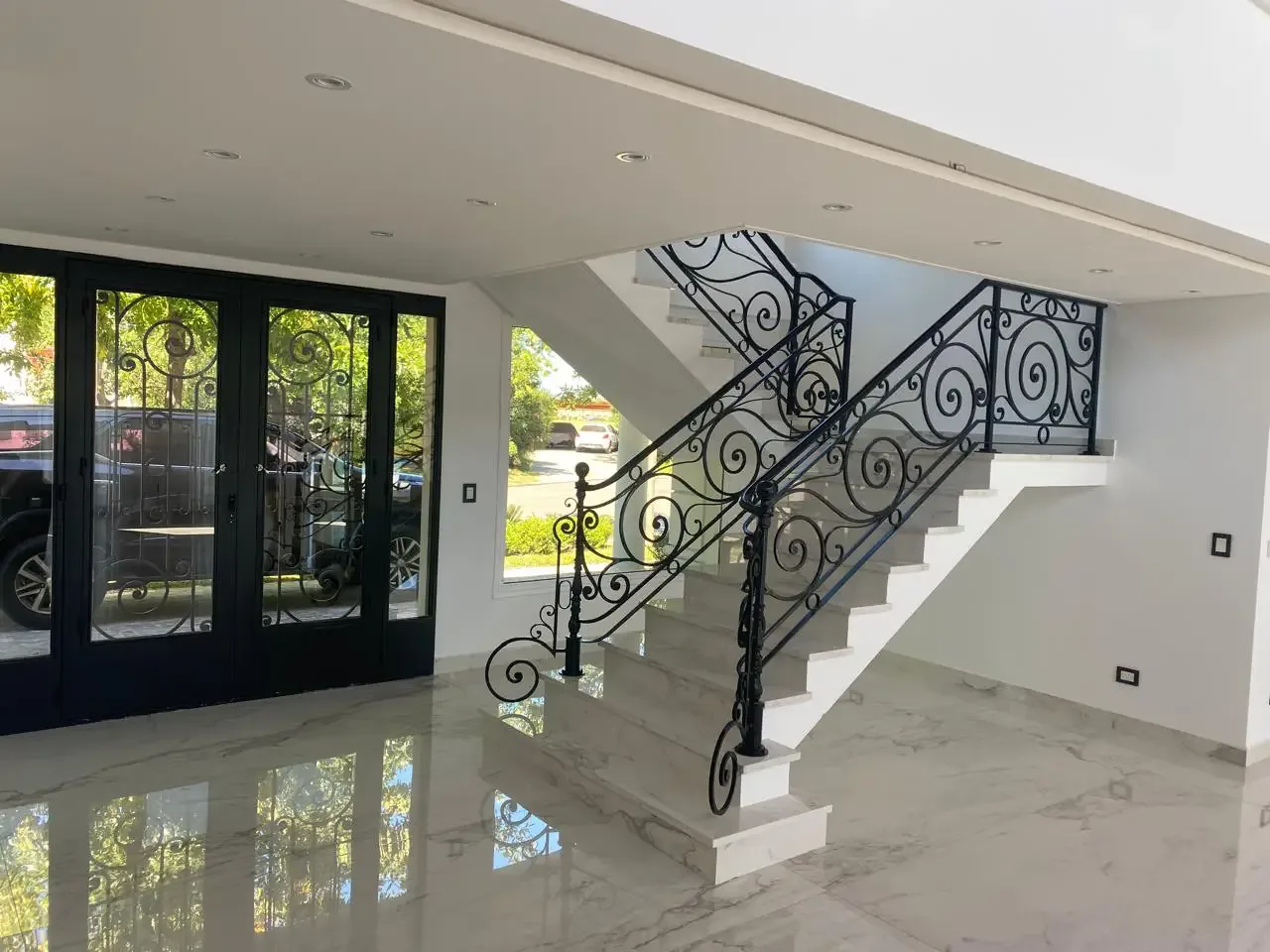 Escalera principal con baranda artística de hierro