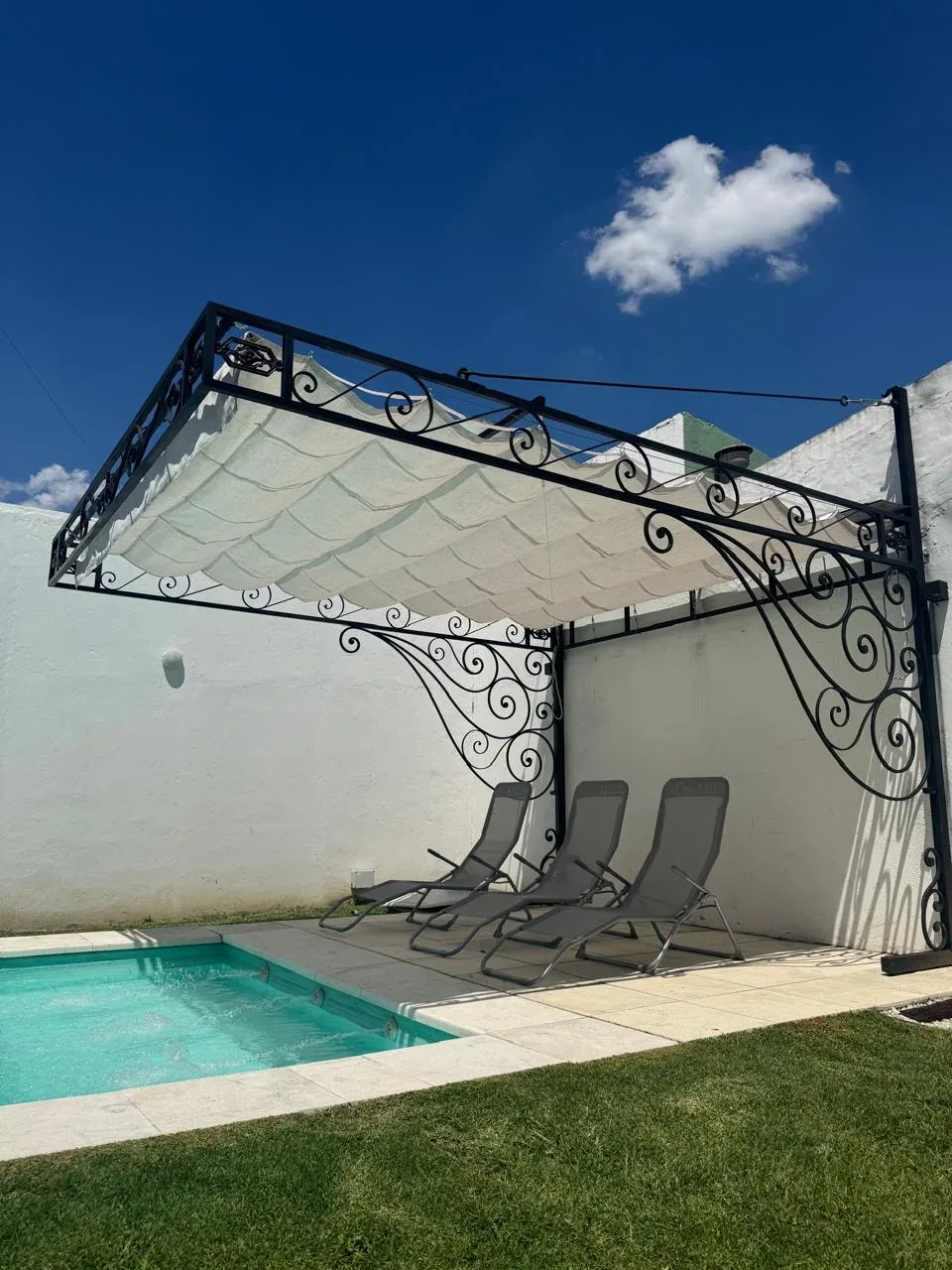 Pérgola ornamental de hierro junto a piscina