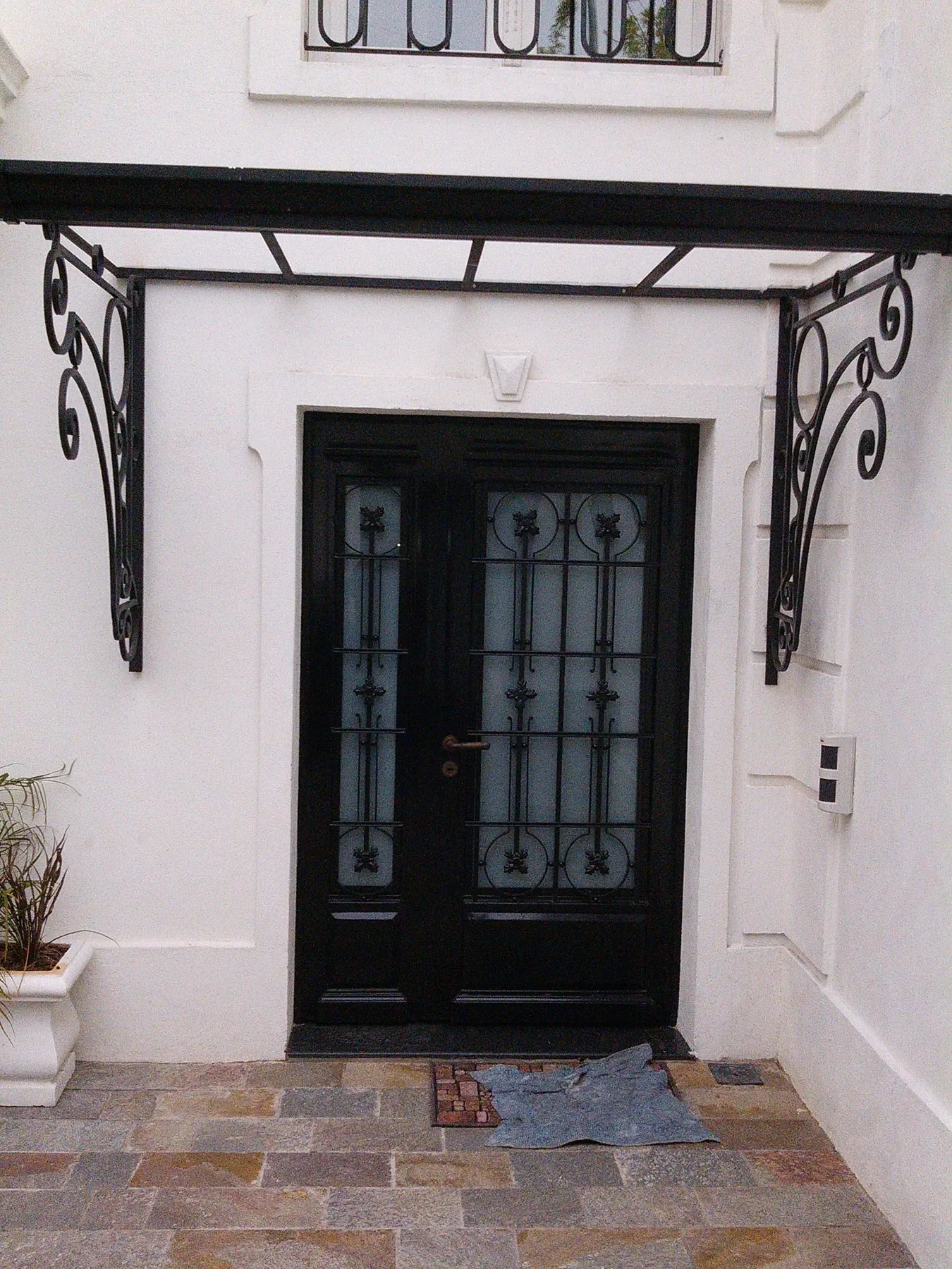 Puerta de hierro negra con marquesina ornamental