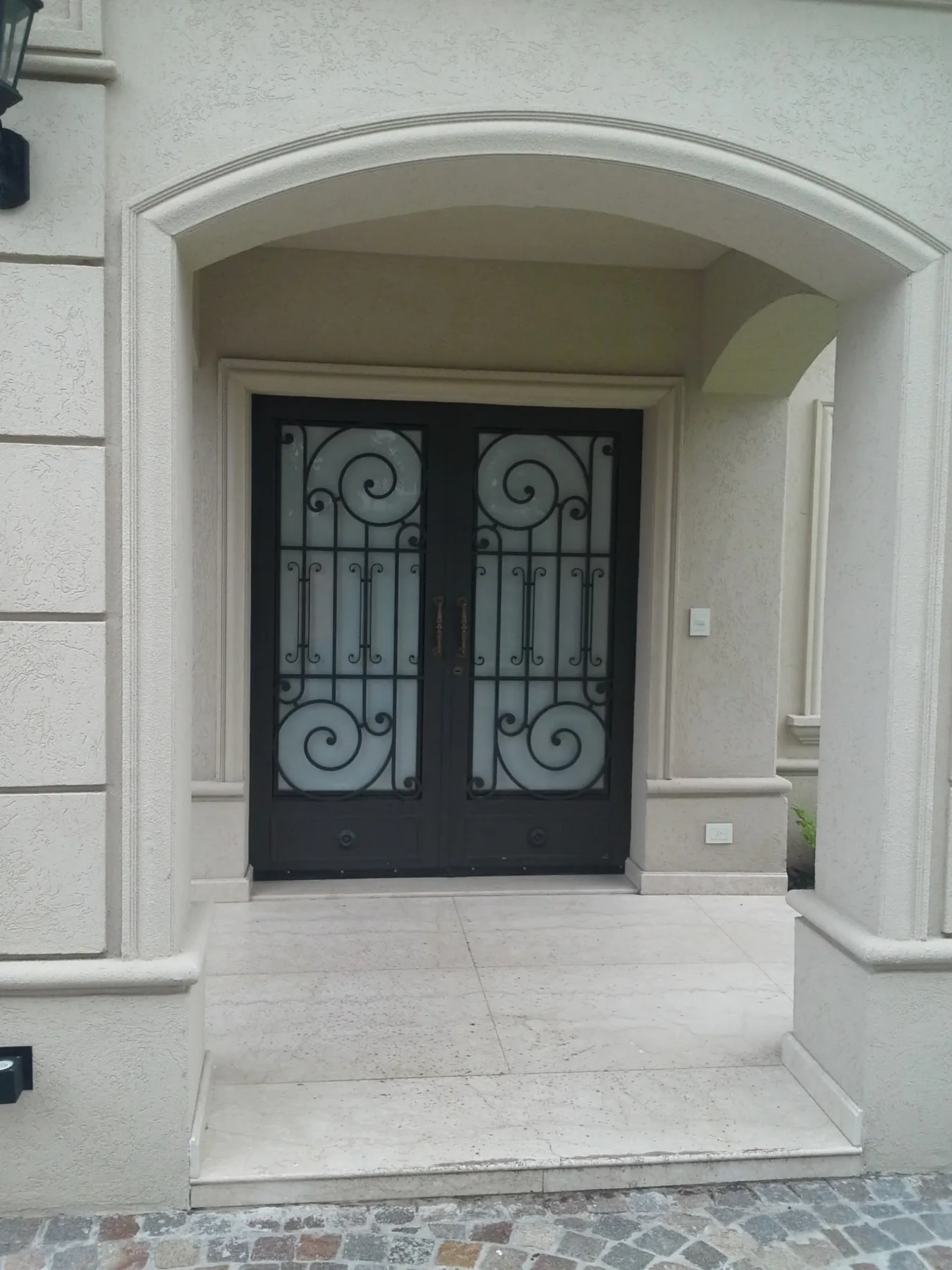 Puerta doble de hierro con vidrio en acceso de vivienda