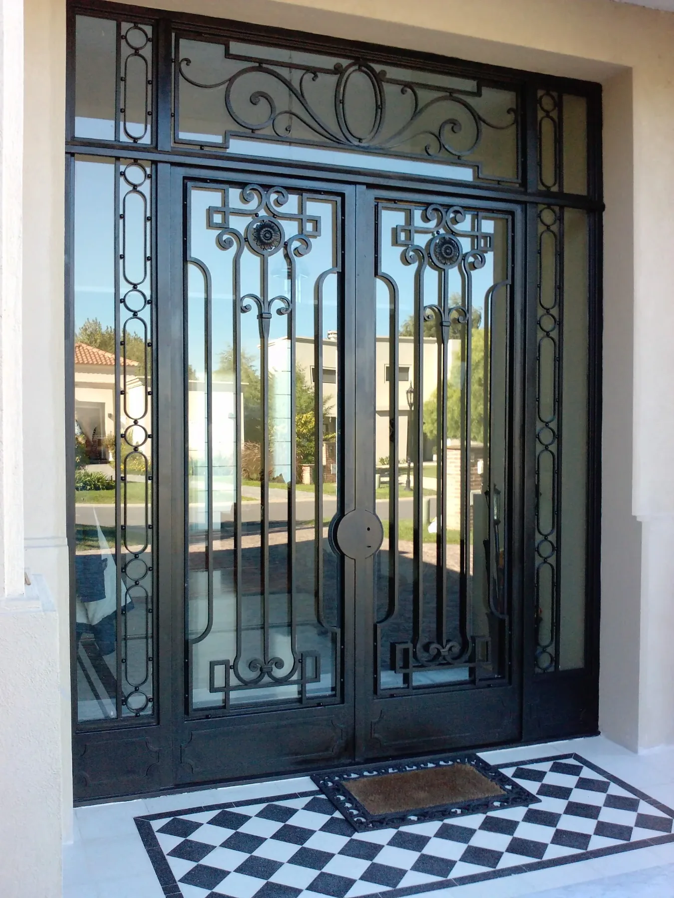 Puerta de hierro de doble hoja con vidrio y paños ornamentales